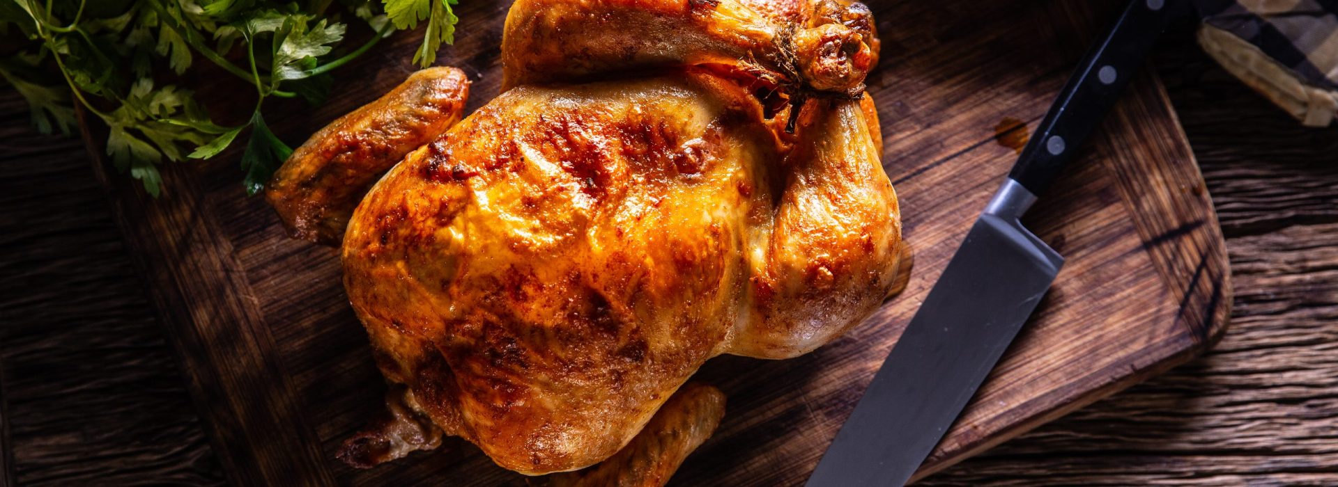 Roast chicken whole on a wooden cutting board - top of view.